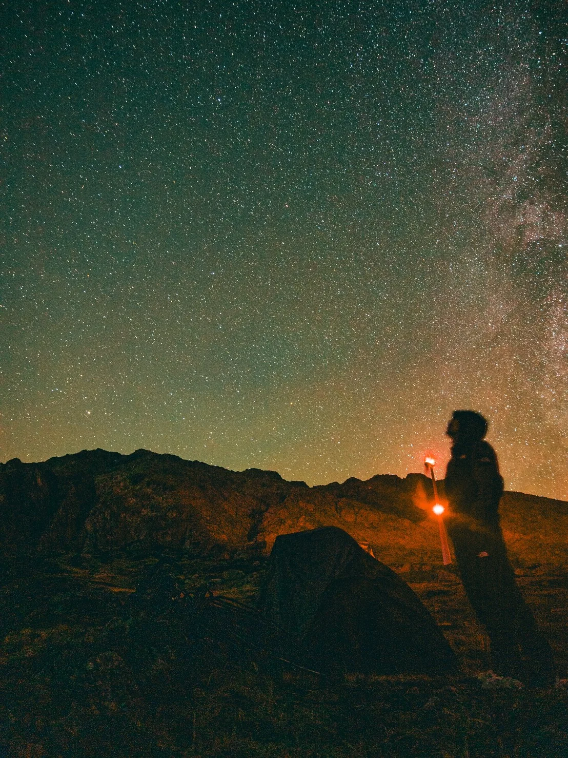 満天の星空の下、テントのそばに立つ櫛原さん